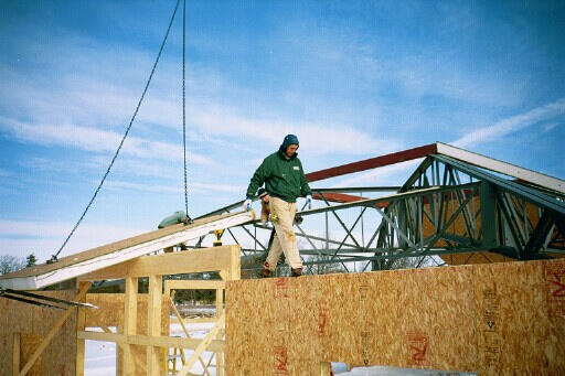 Structured Insulated Panel Installation A man walking along the top of a house frame.